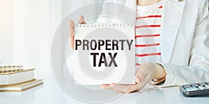 PROPERTY TAX text written on notepad with pencil. Notepad on a folder with diagrams.