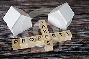 Property Taxes alphabet letter with house model on wooden background