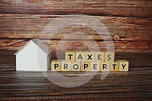 Property Taxes alphabet letter with house model on wooden background