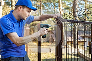 Property territory fencing - man screws metal fence panel
