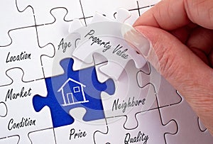 Property Value - female hand with real estate puzzle