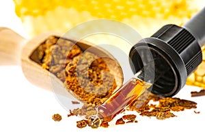 Propolis tincture and a wooden spoon of propolis granules
