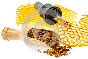 Propolis tincture and a wooden spoon of propolis granules