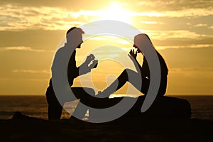 Proposal on the beach with a man asking for marry at sunset