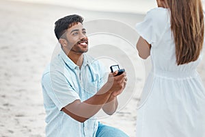 Proposal, surprise and engagement with wedding ring on beach with indian man on knee for love, commitment and marriage