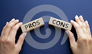 Pros vs Cons symbol. Concept word Pros vs Cons on wooden blocks. Businessman hand. Beautiful deep blue background. Business and