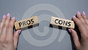 Pros vs Cons symbol. Concept word Pros vs Cons on wooden blocks. Businessman hand. Beautiful grey background. Business and Pros vs