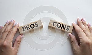 Pros vs Cons symbol. Concept word Pros vs Cons on wooden blocks. Businessman hand. Beautiful white background. Business and Pros