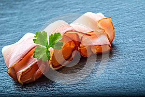 Prosciutto. Curled Slices of Delicious Prosciutto with parsley leaves on granite board. Prosciuto with spice cherry tomatoes photo