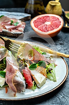 Prosciutto di Parma salad with grapefruit, salad mix, grapefruit, cherry tomatoes, parmesan cheese. Cold snacks. Restaurant menu,