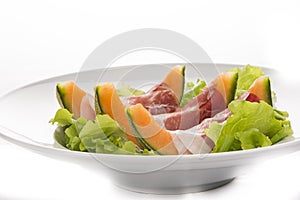 Prosciutto, melon, salad leaf on the white plate