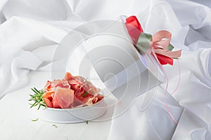 Prosciutto with rosemary in gift box on a white wooden table