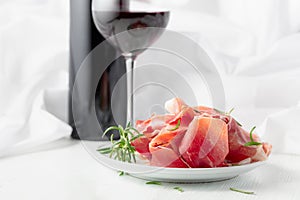 Prosciutto with rosemary and red wine on a white wooden table