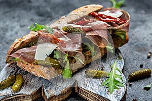 Prosciutto sandwich, Ciabatta with prosciutto, sun-dried tomatoes, gherkins, parmesan and arugula, banner, menu, recipe place for