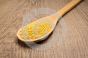 Proso Millet cereal grain. Spoon and grains over wooden table.