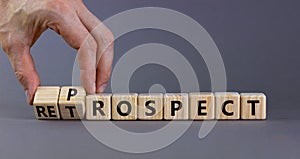 Prospect or retrospect symbol. Businessman turns wooden cubes and changes the word `retrospect` to `prospect`. Beautiful grey photo