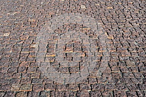 Prospective view on stone road close up. Old pavement of granite. Brown square cobblestone sidewalk. Mock up or vintage grunge tex