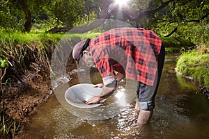 Prospector panning with aluminum pan gold in creek