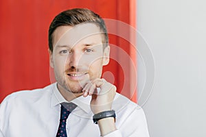 Prosperous entrepreneur in white shirt looks confidently at camera, contemplates new career. Isolated on red and white background