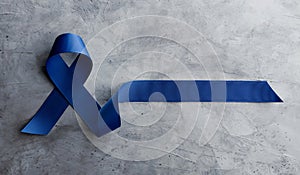 Prostate Cancer Awareness Campaign Concept. Men Healthcare. Close up of a Blue Ribbon Lying on Rough Grey Cement