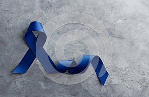 Prostate Cancer Awareness Campaign Concept. Men Healthcare. Close up of a Blue Ribbon Lying on Rough Grey Cement Concrete