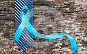 Prostate cancer awareness concept with light blue ribbon on necktie and old aged wood for men`s health care campaign in November