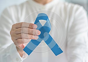 Prostate cancer awareness ribbon for men`s health care concept with light blue bow color in person`s hand