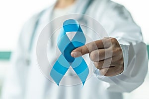 Prostate cancer blue awareness ribbon for men health in November with light blue bow color on medical doctorâ€™s hand in clinical