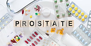 PROSTATE word on wooden blocks on a desk. Medical concept with pills, vitamins, stethoscope and syringe on the background