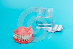 A prosthesis and a glass with a solution. Dental prosthesis care. Full removable plastic denture of the jaws. Upper and lower jaws