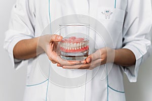 Prosthesis in a glass with a solution. Dental prosthesis care. Full removable plastic denture of the jaws. Two acrylic dentures.