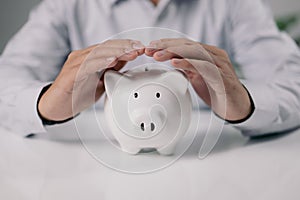 Protect your money, Man hand protect piggy bank on white table