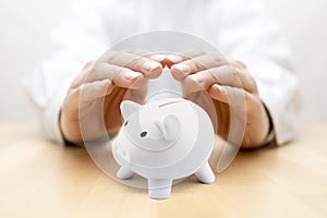 Protect your money. Small piggy bank covered by hands