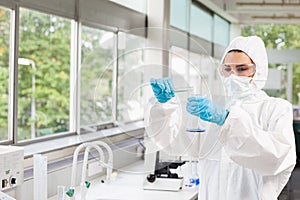 Protected female scientist pouring liquid