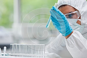 Protected science student looking at a test tube