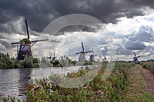 Protected windmills in the gloomy autumn landscape near Kinderdijk, South Holland, Netherlands.