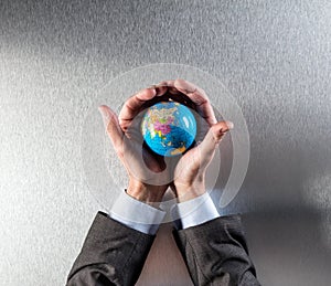 Protecting businessman holding the earth within hands for environment care