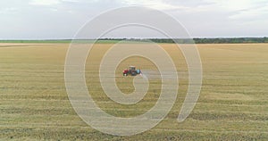 Protecting fields from pests. Large wheat field drone view. A tractor sprays a wheat field, a top view.