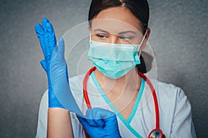 Protection against contagious disease, coronavirus. Beautiful female doctor or nurse wearing protective mask and latex or rubber