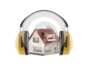 Protection against noise. Hearing protection yellow ear muffs with house miniature isolated on white background photo