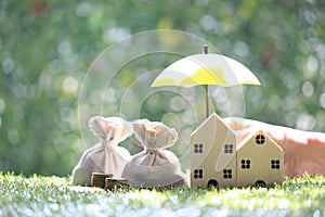 Protection, Coins money in the bag under the umbrella and model house on natural green background, Finance insurance and Safe