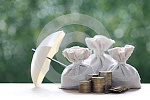 Protection, Coins money in the bag under the umbrella on natural green background, Finance insurance and Safe investment concept