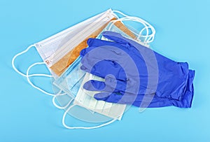 Protection concept - blue latex medical gloves and colored surgical mask on blue background