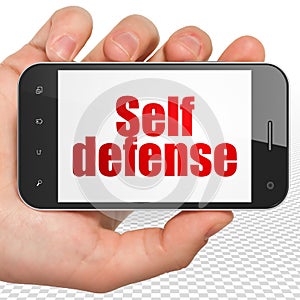 Protection concept: Hand Holding Smartphone with Self Defense on display