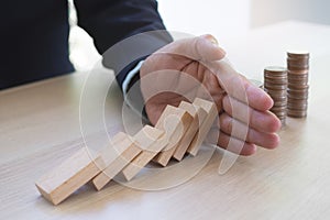 Protection finance from domino effect concept. Hands stop domino effect before destroy stack of money