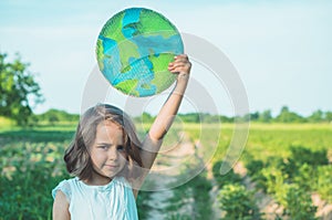 Protection and love of earth. Little girl holding planet in hands against green spring background. Earth day holiday concept.