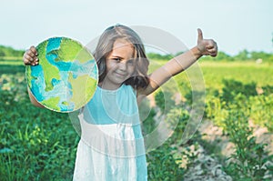 Protection and love of earth. Little girl holding planet in hands against green spring background. Earth day holiday concept.