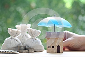 Protection, Model house under the umbrella and coins money in the bag on natural green background, Finance insurance and Safe