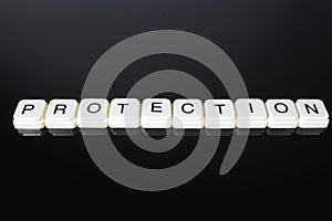 Protection text word title caption label cover backdrop background. Alphabet letter toy blocks on black reflective background. Whi