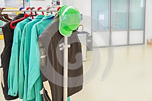 Protective clothes and green safety helmet on a coat rack at factory